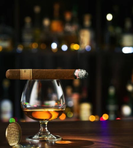 Closed up view of glass of coignac with cigar on top on white back