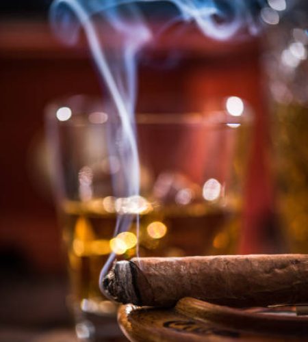 Cuban cigar smoke and luxurious Cognac in carafe.